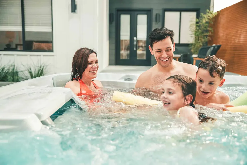Family laughing together in a backyard hot tub